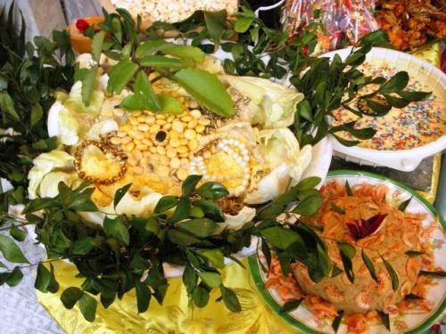 特別の枝葉や金銀のアクセサリーが飾られた神様への捧げ物の料理