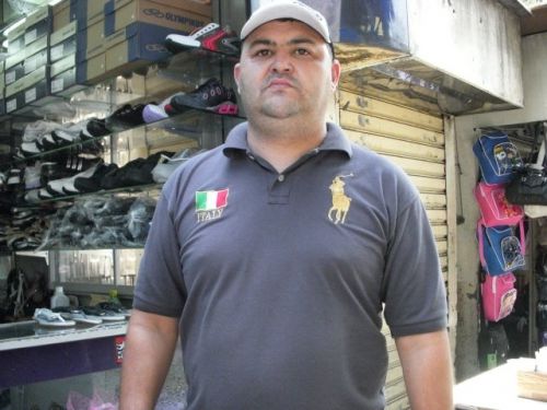 大きなポロのマークとイタリアの国旗柄のワッペンが付いたポロシャツを着る人