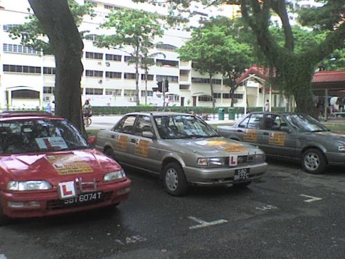 フリーの教官たちを集めた会社の連絡先を貼った車が、駅前駐車場に並んでいます
