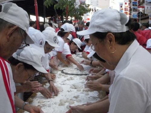 毎朝リベルダーデ広場でラジオ体操を行う男女がつきたての餅を丸める