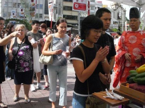紅白餅をもらった後、南米神宮の茅の輪をくぐってお祈りする人々