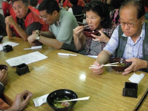 ｢餅つき祭り｣でふるまわれたお雑煮を食べる人々
