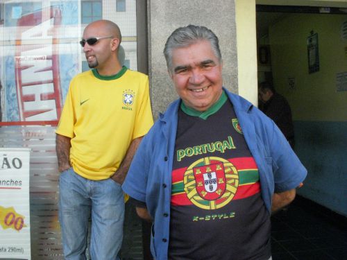ポルトガル国旗の柄のＴシャツを着たサンパウロで暮らすポルトガル人。後ろはブラジル人男性。