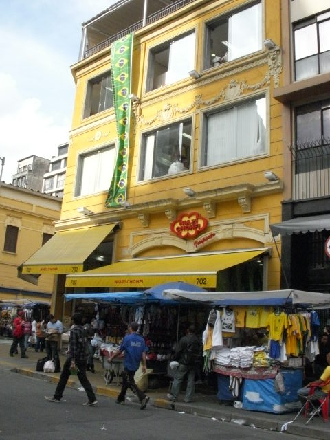 ビルの上からブラジル国旗がプリントされた生地がかけられ、前の露天市ではブラジルＴシャツも販売