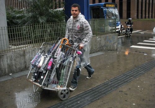 小雨が降り出し、傘を売るために駅前に向う男性