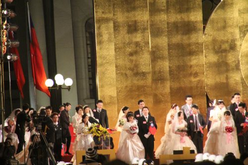 国旗掲揚前にステージに上がった100組の新婚さん