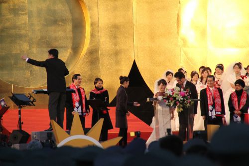 馬英九総統夫婦（指揮者と指示役の女性の間にいる２人）と蕭萬長（シャオ・ワンジャン）副総統夫婦（署名する新郎の右側にいる２人）に見守られ、婚姻証明に署名する100組の新婚さんの代表