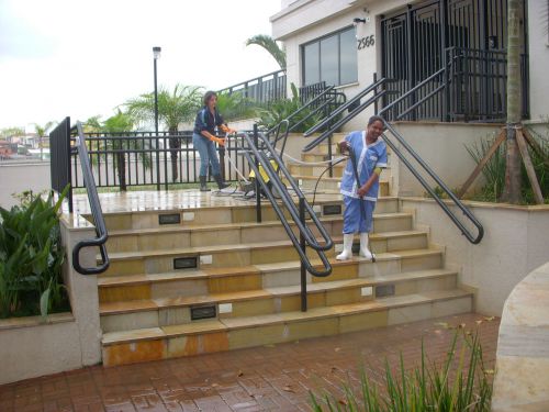 アパートの正門で高水圧マシンでゴミを寄せながら水をまく人