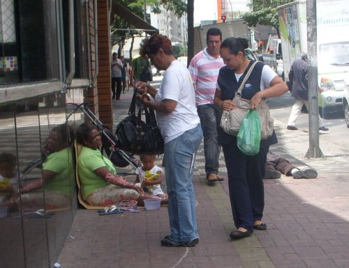 物乞いをする女性と一緒にいる子供に小銭を渡そうとする女性たち