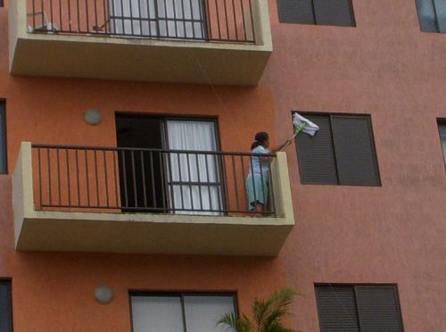 家の雨戸を掃除するファシネイラ（掃除婦）として働くお手伝いさん