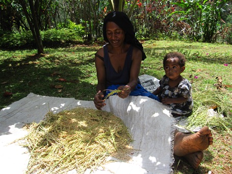 穂についた実を丁寧に摘み取る若いお母さん