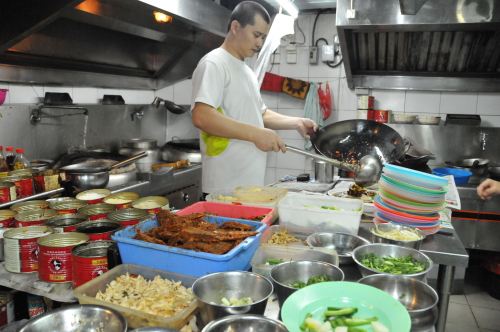 厨房で中華鍋を振り料理を手際よく皿によそう馬さん。三つのコンロを使いこなし、次々と注文をさばく