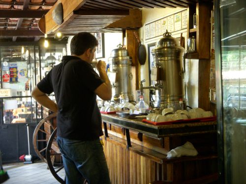 コーヒー専用のタンクとストックされたコーヒーを食後に無料で立ち飲みする男性