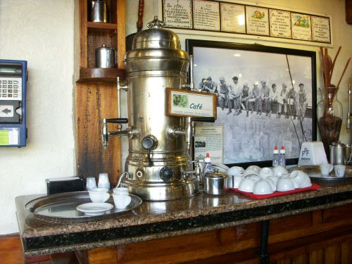 濾されたコーヒーの入ったタンクと陶器のコップとプラスチックコップ（左奥）など