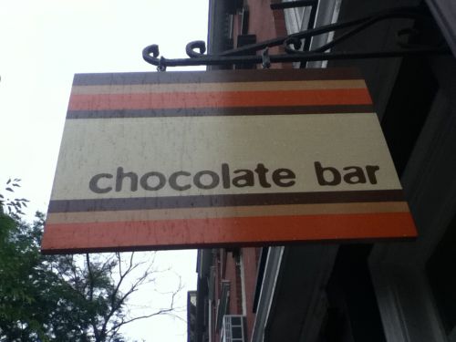店のドアの上にある標識。チョコレートバーは「板チョコ」という意味も「チョコレートが並べてある店」という意味もあるからかけことばになっています