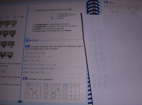 掛け算の説明をするブラジルの算数の教科書と、3の段を考える時の図での説明（教科書の上の用紙）。