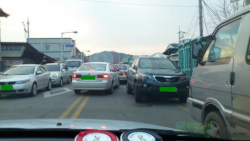 右側通行の道、進行方向と逆に堂々と駐車された車が見えます