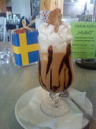 ポーランド風アイスコーヒー、メニューにある「アイスコーヒー」を注文すると、アイスクリームがコーヒーの中に入ってチョコレートソースや生クリームで飾られた、一見パフェのように見えるドリンクが提供されます。（スウェーデンの国旗はこのレストランの卓上には各国の国旗の置物が設置されていたため、写真はポーランドです）