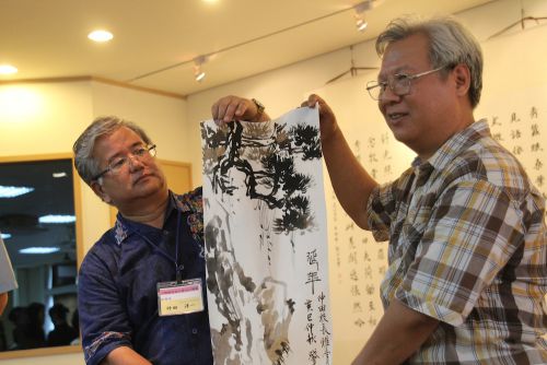 水墨画の贈呈を行なう小禄高校の仲田洋一校長(左)と台北市立第一女子高級中學(以下、通称の北一女:ベイイーニュィ)の黄肇基(ホワン・ジャオジー)先生(右)