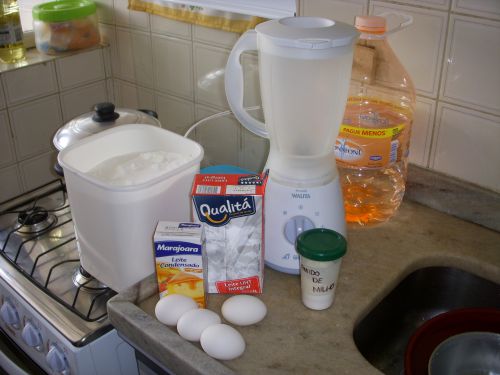 コンデンスミルクプリンの材料。大きな白い箱は砂糖（カラメル用）、小さなパックはコンデンスミルク、大きなパックは牛乳、卵、コーンスターチ（緑のふた）。砂糖以外をミキサーにかける