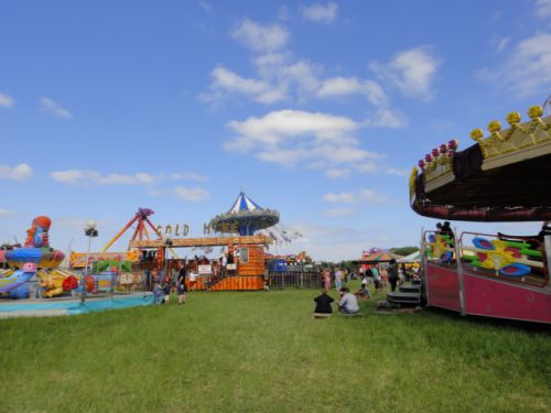 目に鮮やかなグリーンと青い空の元、カラフルな乗り物がマッチ