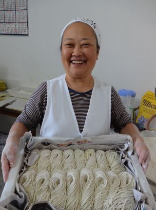出来立てのラーメンの生麺を持つ小川直美さん