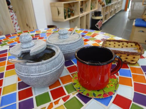 ミナスジェライス州特産のぺドラサボンの容器に入った砂糖とほうろうびきのコップに注がれたコーヒー