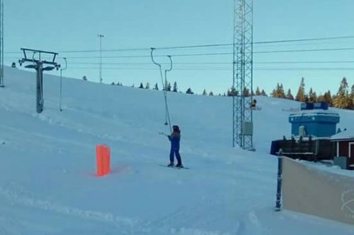 立ち乗りリフトに乗る息子。スキーポールは、手に持つか、足の間に挟めて、登っていきます。