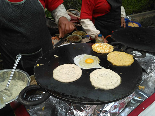 厚い鉄板でネワール料理のバラ（豆生地のパンケーキ）を焼いています。