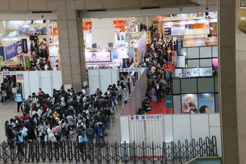ブースに並ぶ人たち(左半分)と壁にもたれ、座り込んでいる人たち(右半分)