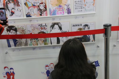 お気に入りの漫画家の色紙を撮影する来場者