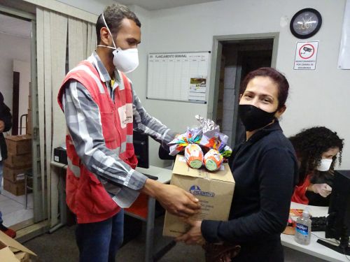 国際赤十字社のボランティアから卵型チョコレートとセスタ・バジカを受け取る女性