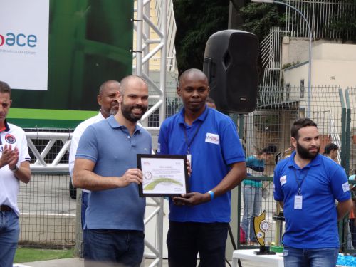 2018年のブラジル難民サッカーワールドカップを訪問して主催者のNGOの代表から感謝状を受け取るブルーノ・コバス氏