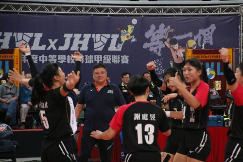 劉忠賢監督(奥で選手たちが喜ぶ姿を見つめている黒のポロシャツの男性)